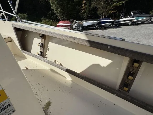 Slide: The Image of 1990 Mako 201 boat interior with exposed storage compartment, surrounded by parked boats. - 16