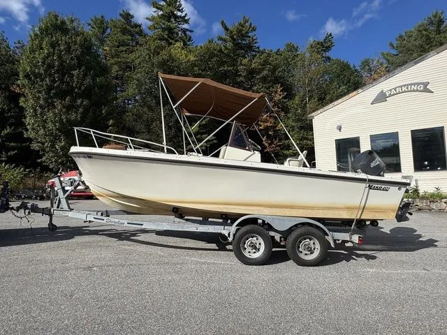 Slide: The Image of 1990 Mako 201 boat on trailer, parked outdoors near building, under clear blue sky. - 2