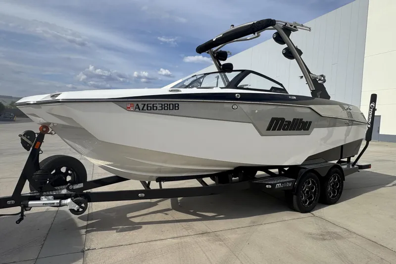 Slide: The Image of 2023 Malibu M220 boat on trailer, parked outdoors under a cloudy sky. - 10