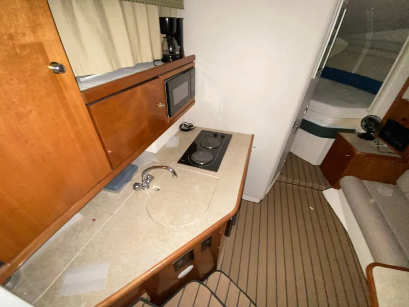 Slide: The Image of 1999 Trojan 320 Express yacht interior with kitchenette, featuring wood cabinetry and modern appliances. - 10