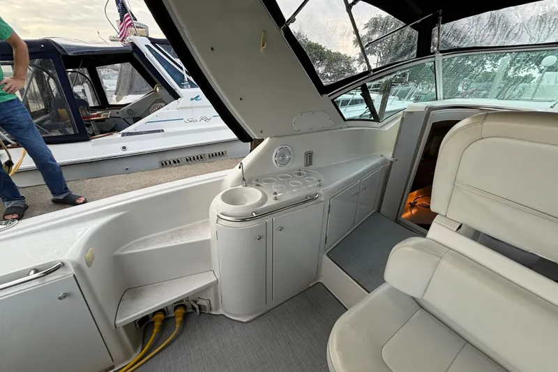 Slide: The Image of 1999 Trojan 320 Express boat interior with seating and storage, docked beside another vessel. - 13