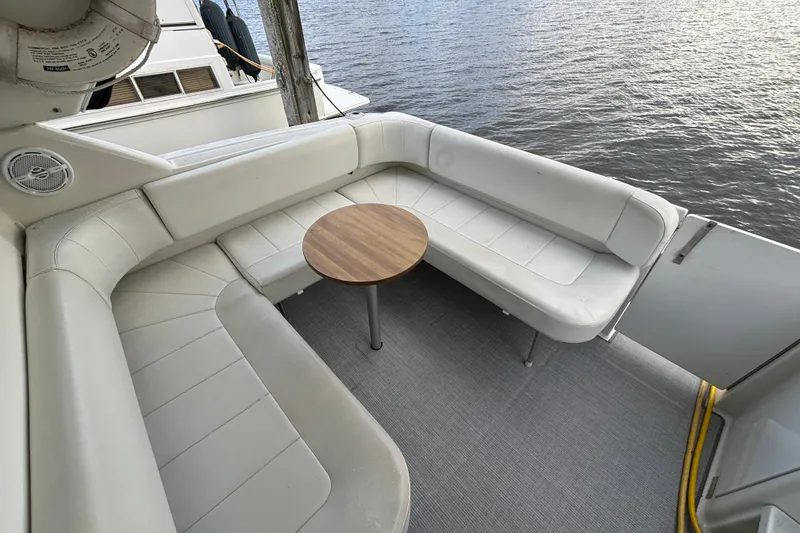 Slide: The Image of 1999 Trojan 320 Express boat with white seating and wooden table on deck. - 14