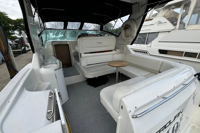 Slide: The Image of 1999 Trojan 320 Express boat interior with white seating and small round table. - 17
