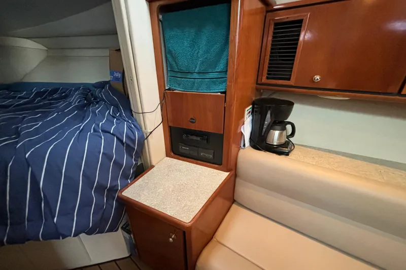 Slide: The Image of 1999 Trojan 320 Express cabin interior with bed, coffee maker, and wooden cabinetry. - 28