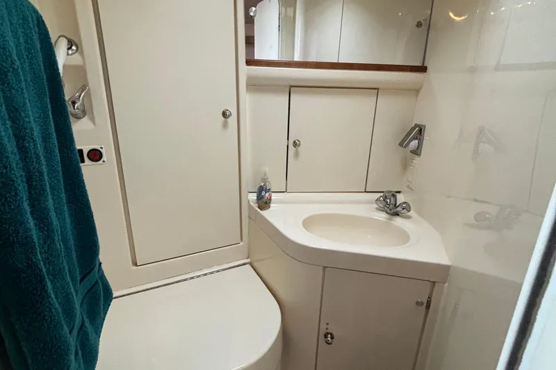 Slide: The Image of 1999 Trojan 320 Express yacht bathroom with sink, storage cabinets, and teal towel. - 30