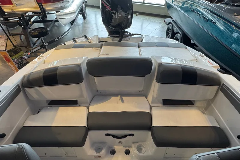 Slide: The Image of 2026 Tahoe T21 boat interior with cushioned seating and motor, displayed in showroom. - 8