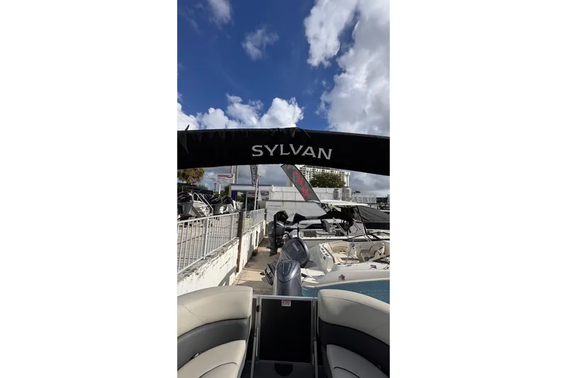 Slide: The Image of 2024 Sylvan 822 LZ boat with canopy, displayed outdoors under a partly cloudy sky. - 21