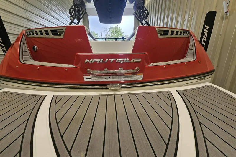 Slide: The Image of 2016 Nautique Super Air Nautique 210 boat, red and white, rear view in storage. - 10