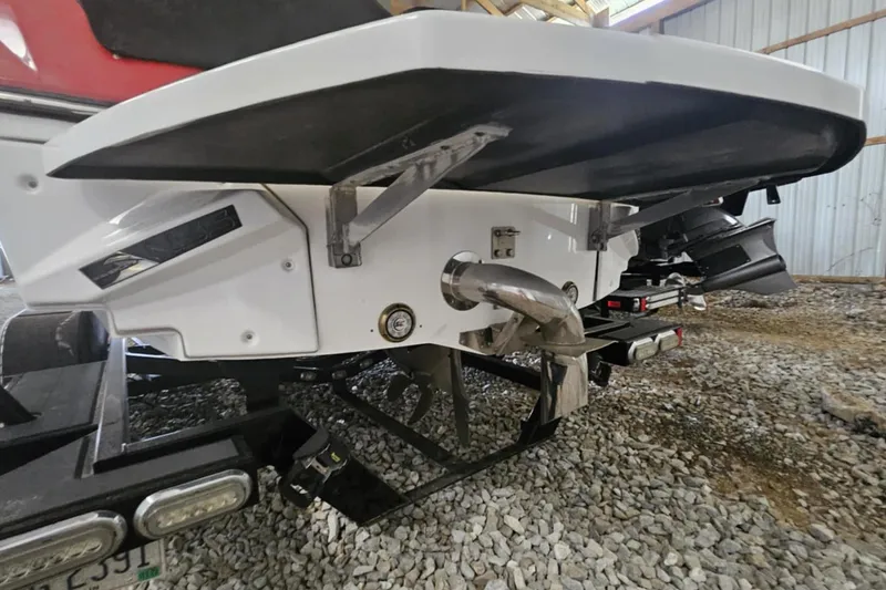 Slide: The Image of 2016 Nautique Super Air Nautique 210 boat rear view in storage, showcasing exhaust and propeller. - 12