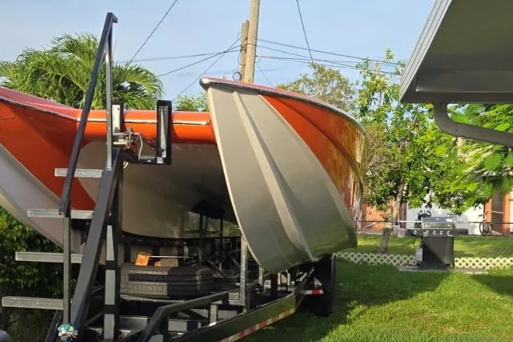 Slide: The Image of 2009 Nor-Tech Supercat 3600 boat on trailer, vibrant orange hull, parked outdoors. - 26