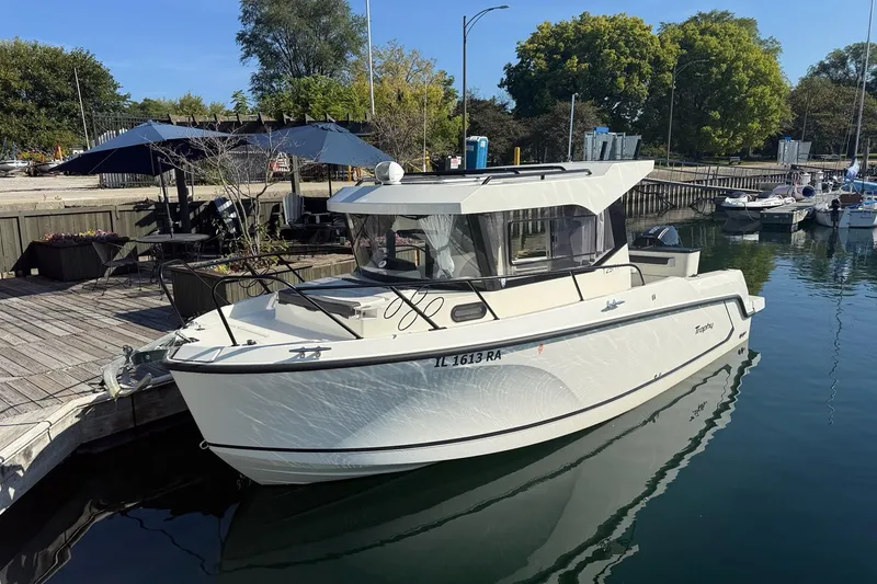 The Image of 2024 Bayliner Trophy T25 Pilothouse docked at a marina, surrounded by calm water. - 0
