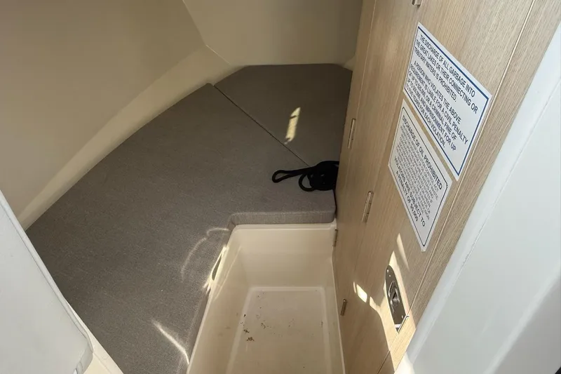 Slide: The Image of 2024 Bayliner Trophy T25 Pilothouse cabin interior with cushioned seating and storage area. - 34