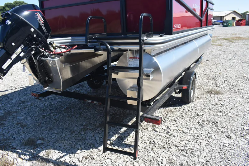 Slide: The Image of 2026 Lowe LS 190 pontoon boat with motor and ladder on gravel surface. - 9