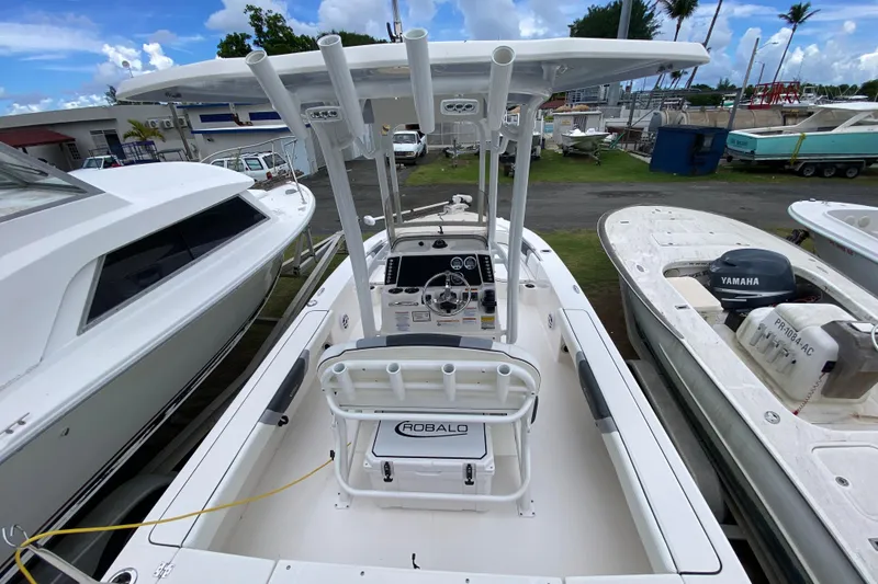 Slide: The Image of 2023 Robalo 226 Cayman boat with T-top, docked among other vessels. - 3