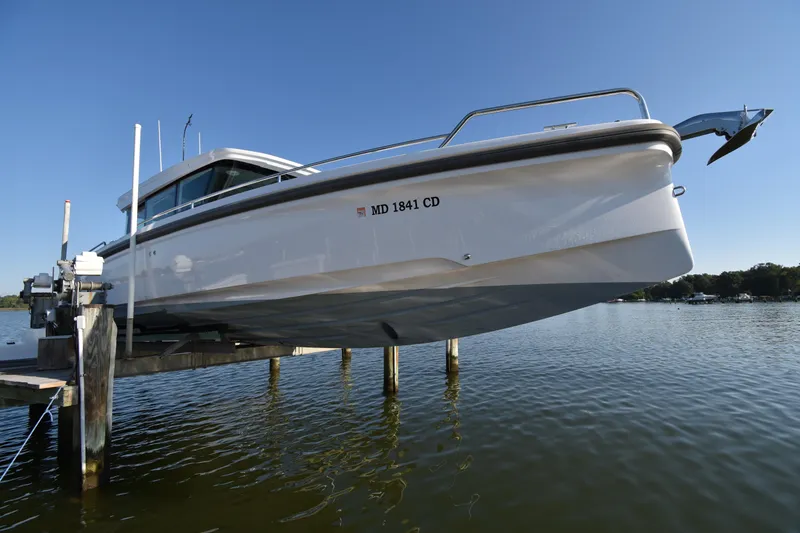 Slide: The Image of 2023 Axopar 37XC Wet Bar boat on lift over water, clear sky background. - 7