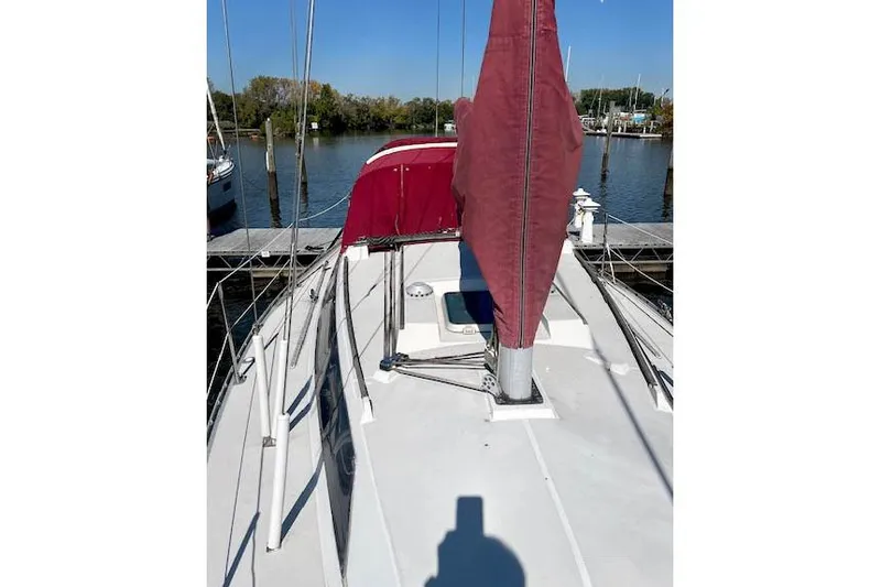 Slide: The Image of 1988 O'Day 322 sailboat deck with red sail cover, docked by calm waters. - 4