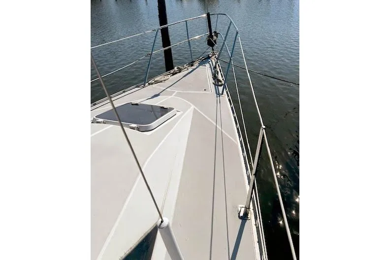 Slide: The Image of 1988 O'Day 322 sailboat deck view with railing, docked on calm water. - 7