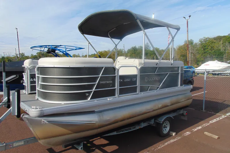Slide: The Image of 2022 Godfrey Sweetwater 1680 CX pontoon boat on trailer, parked outdoors. - 1