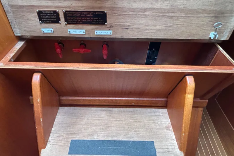 Slide: The Image of Interior view of a 1992 Najad 390 sailboat showing wooden storage compartment and control switches. - 72