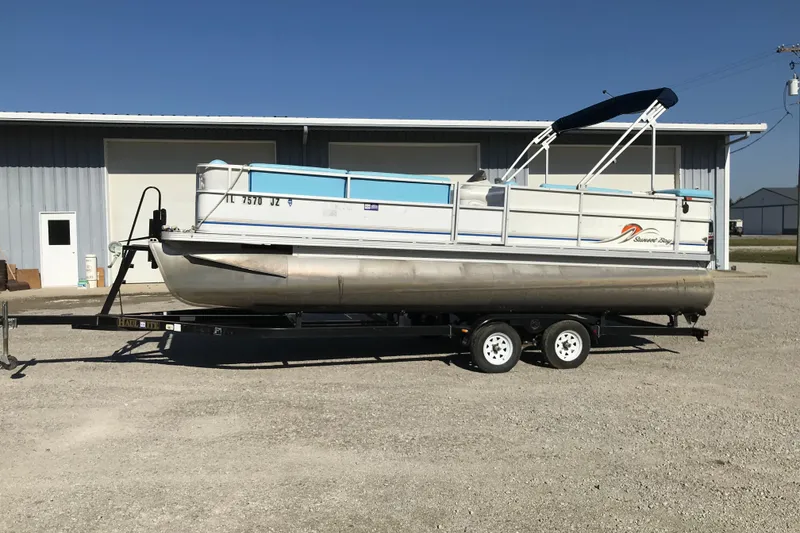 Slide: The Image of 2006 Sunset Bay CRUISE DELUXE pontoon boat on trailer, parked outside a building. - 3