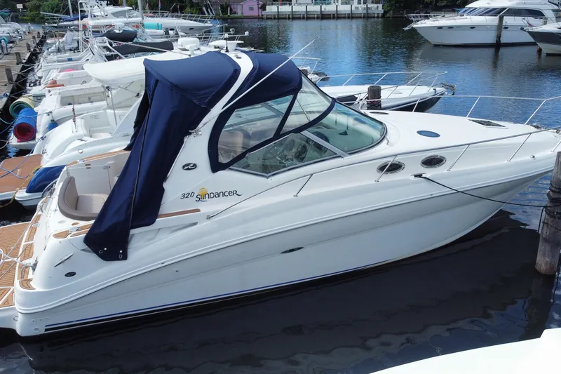Slide: The Image of 2002 Sea Ray 320 Sundancer yacht docked at marina, featuring blue canopy. - 10