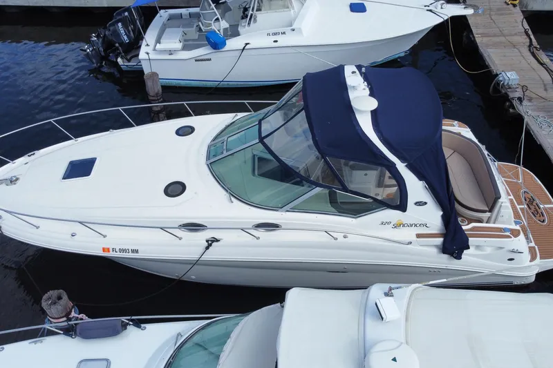 Slide: The Image of 2002 Sea Ray 320 Sundancer docked at marina, featuring sleek design and blue canopy. - 12
