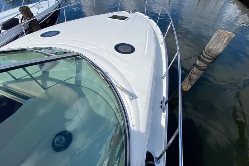 Slide: The Image of 2002 Sea Ray 320 Sundancer yacht docked, showcasing sleek design and glass windshield. - 15