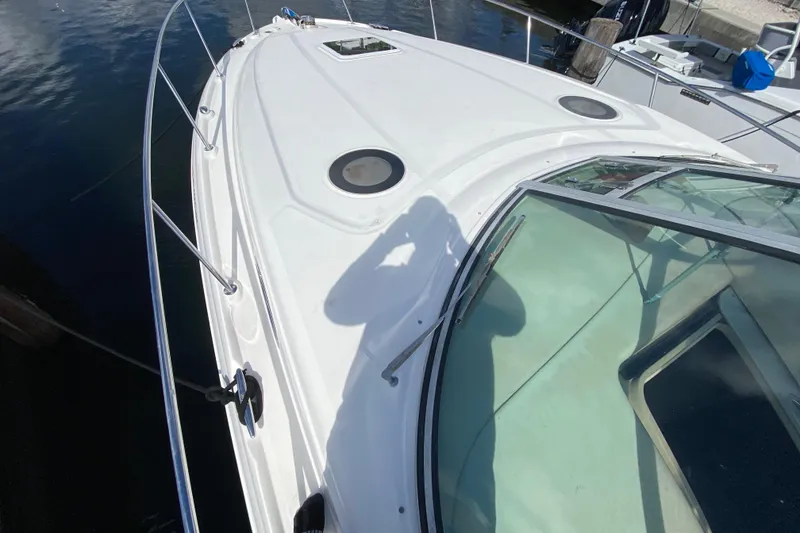 Slide: The Image of 2002 Sea Ray 320 Sundancer boat deck with shadow and railing, docked on calm water. - 16