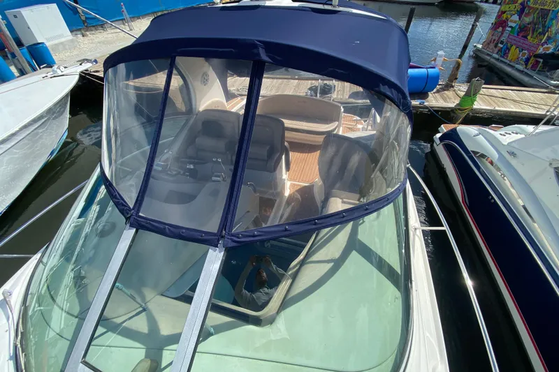 Slide: The Image of 2002 Sea Ray 320 Sundancer boat docked, featuring a blue canopy and clear windshield. - 19