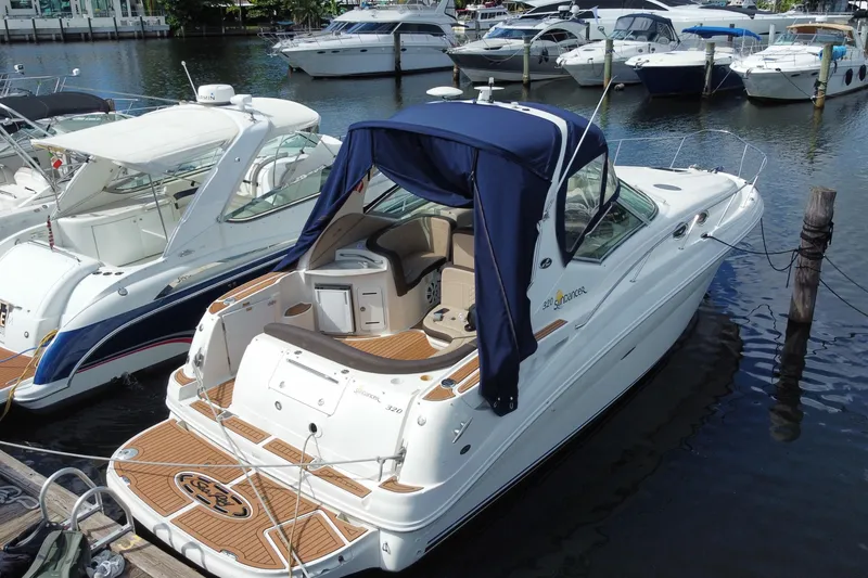 Slide: The Image of 2002 Sea Ray 320 Sundancer docked at marina, featuring sleek design and blue canopy. - 20