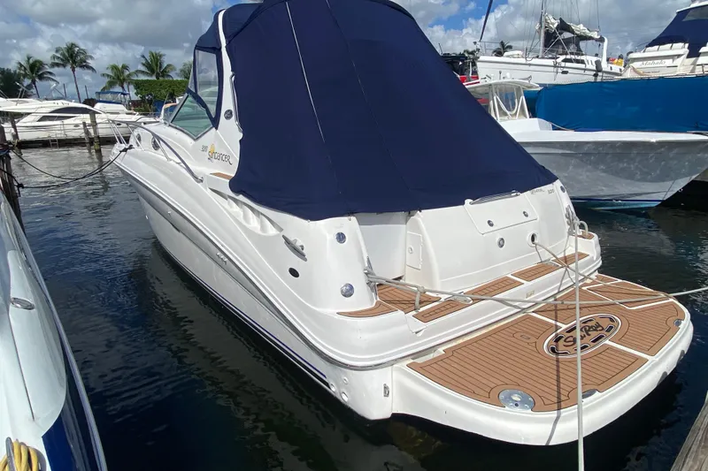 Slide: The Image of 2002 Sea Ray 320 Sundancer yacht docked, featuring a blue canopy and wooden deck. - 23