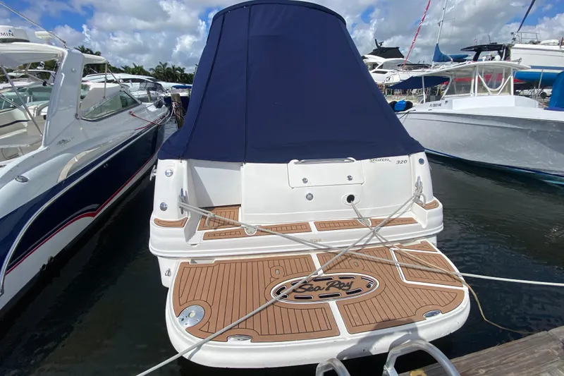 Slide: The Image of 2002 Sea Ray 320 Sundancer docked, featuring a covered deck and sleek design. - 25