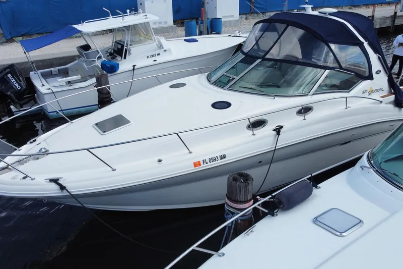 Slide: The Image of 2002 Sea Ray 320 Sundancer docked at marina, featuring sleek design and blue canopy. - 3