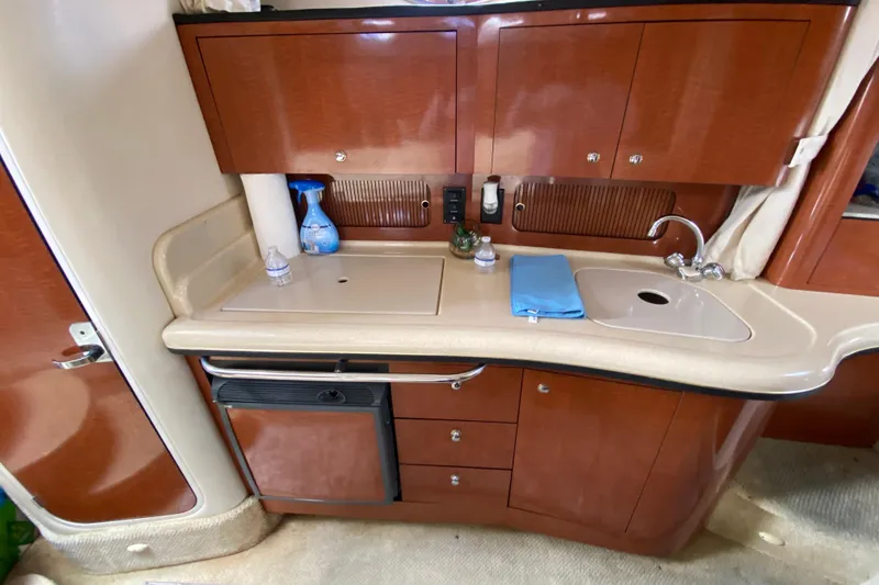 Slide: The Image of 2002 Sea Ray 320 Sundancer galley with sink, cabinets, and mini fridge. - 39