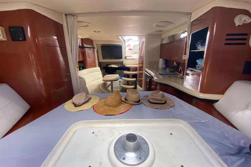 Slide: The Image of Interior of 2002 Sea Ray 320 Sundancer yacht with hats on table, cozy seating, and kitchenette. - 41