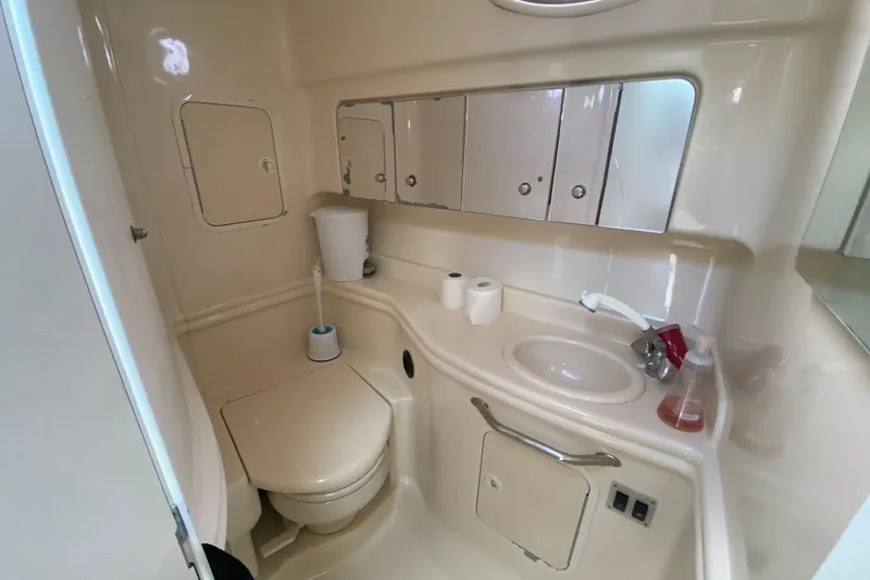 Slide: The Image of 2002 Sea Ray 320 Sundancer bathroom with toilet, sink, and storage cabinets. - 43