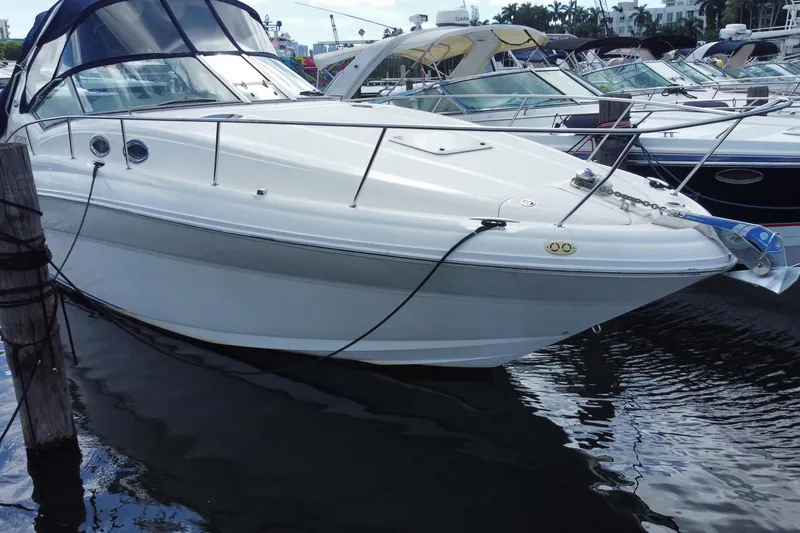 Slide: The Image of 2002 Sea Ray 320 Sundancer docked at marina, showcasing sleek design and white exterior. - 7