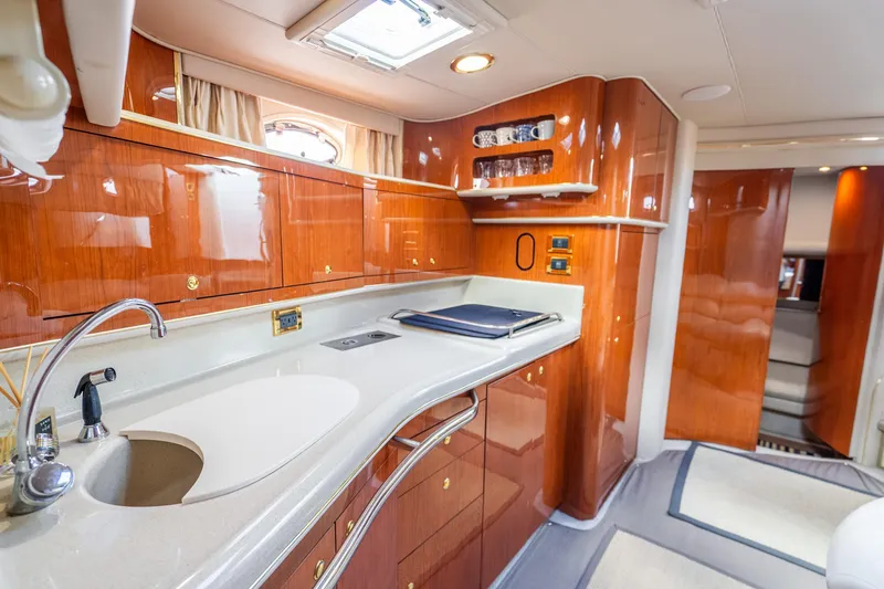 Slide: The Image of 1998 Sea Ray 450 Sundancer yacht interior with polished wood cabinetry and modern kitchen amenities. - 16