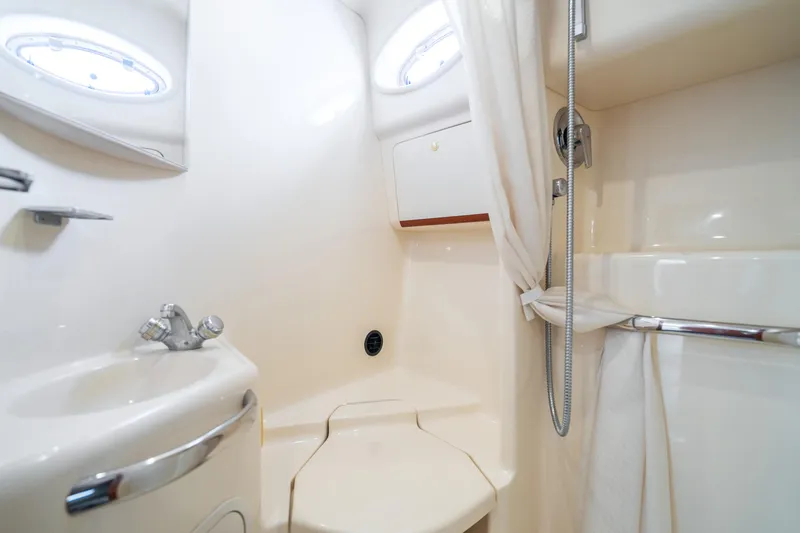 Slide: The Image of 1998 Sea Ray 450 Sundancer bathroom with sink, shower, and porthole windows. - 21