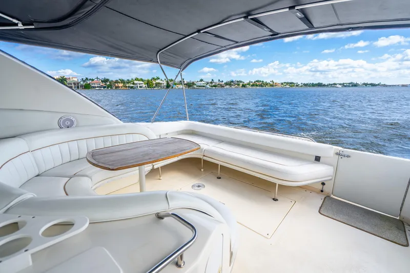 Slide: The Image of 1998 Sea Ray 450 Sundancer yacht interior with white seating and wooden table, overlooking water. - 28