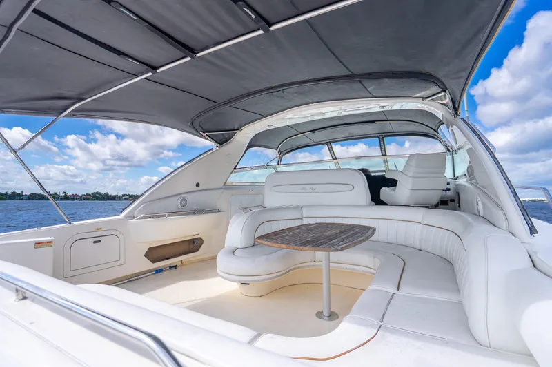 Slide: The Image of 1998 Sea Ray 450 Sundancer yacht interior with white seating and wooden table, under a canopy. - 32