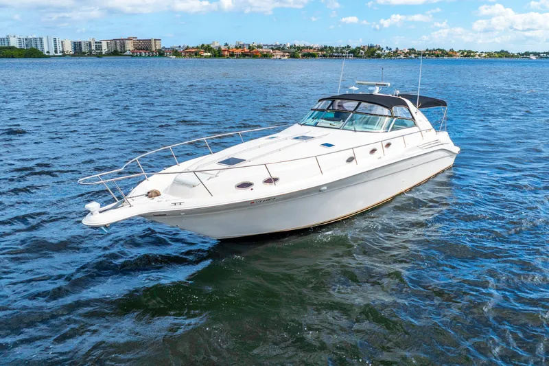 Slide: The Image of 1998 Sea Ray 450 Sundancer yacht cruising on open water under a clear blue sky. - 9