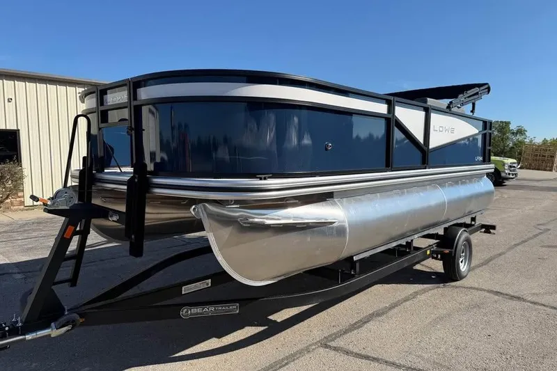 Slide: The Image of 2026 Lowe LF 194 pontoon boat on trailer, parked outdoors under clear sky. - 1