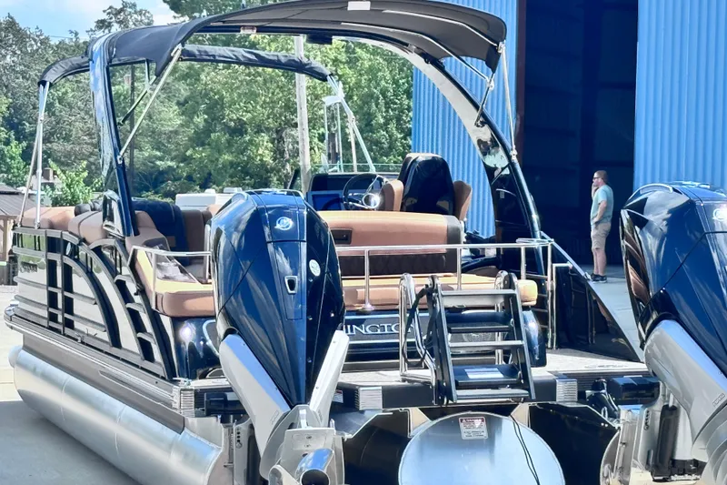 Slide: The Image of 2026 Bennington 27RSBAT2 pontoon boat with dual engines, docked near a blue building. - 11