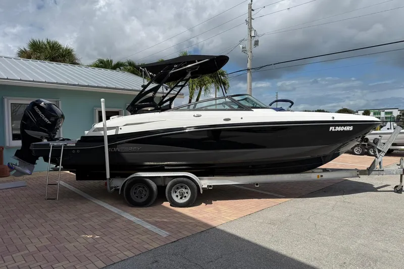 Slide: The Image of 2018 Monterey M-65 boat on trailer, parked outdoors under cloudy sky. - 12