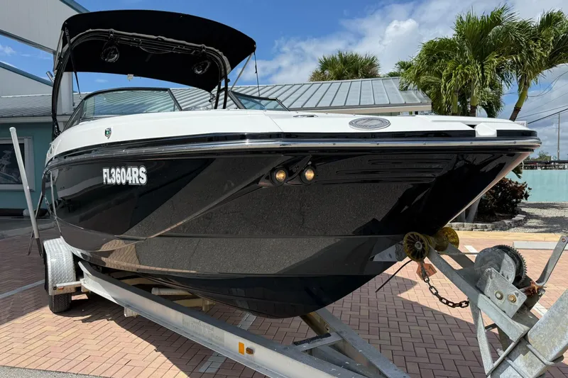 Slide: The Image of 2018 Monterey M-65 boat on trailer, black hull, parked near palm trees. - 13