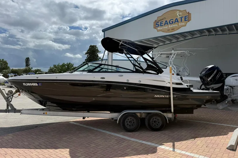 Slide: The Image of 2018 Monterey M-65 boat on trailer at Seagate Marine Sales, featuring sleek black and white design. - 2
