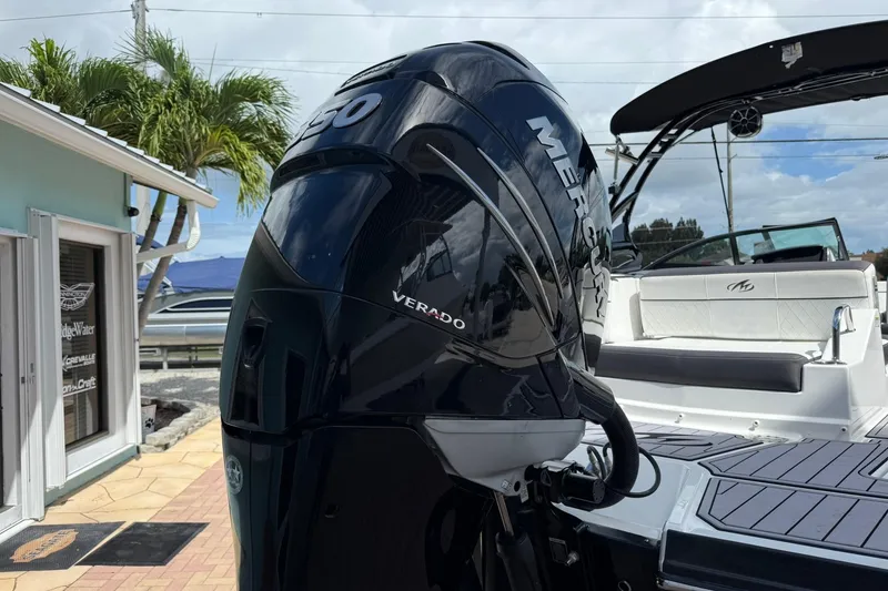 Slide: The Image of 2018 Monterey M-65 boat with Mercury Verado engine, docked near a building and palm trees. - 9