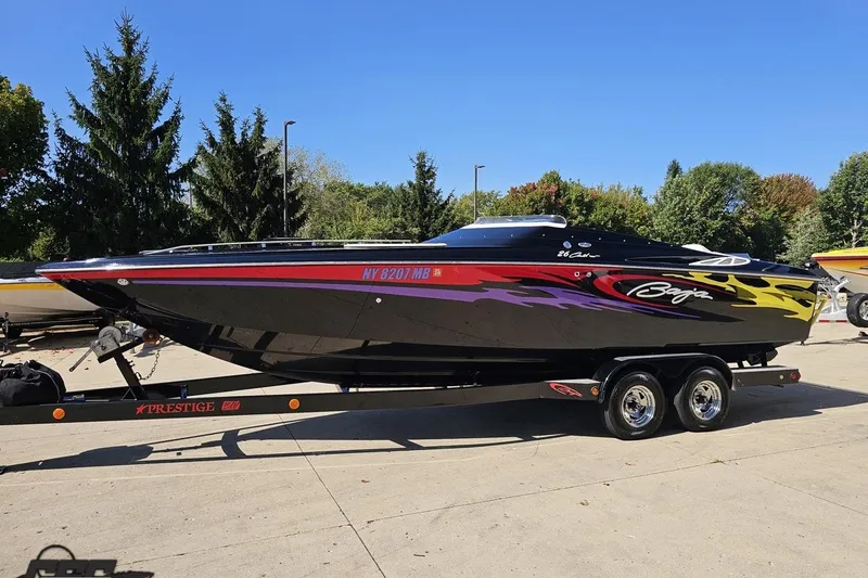 Slide: The Image of 2005 Baja 25 Outlaw speedboat on trailer, vibrant graphics, parked outdoors. - 19
