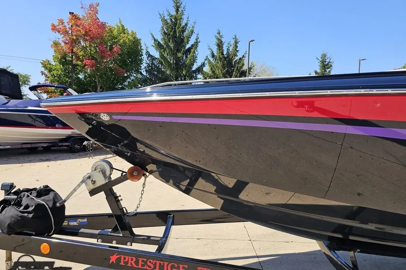 Slide: The Image of 2005 Baja 25 Outlaw boat on trailer, vibrant red and black design, outdoor setting. - 21